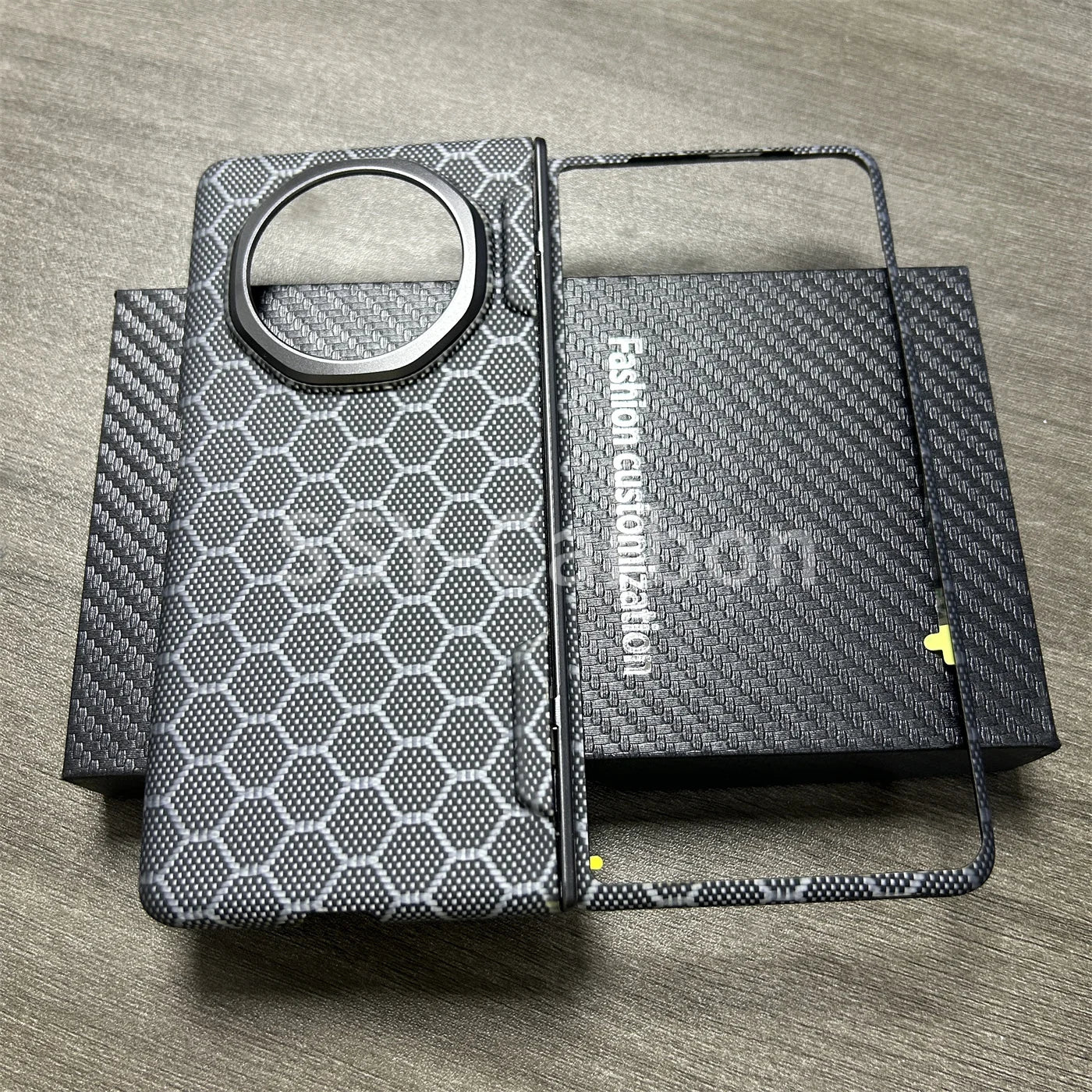 Black and grey honeycomb-patterned phone case with a large circular camera cutout and a separate front screen frame.