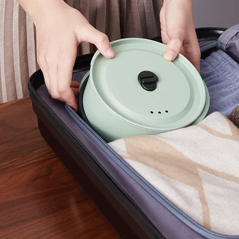 Green electric cooking pot with lid being placed on the portable base