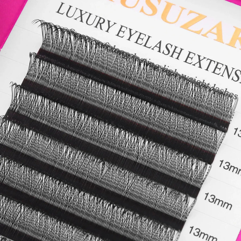 Rows of black, synthetic 13mm individual eyelash extensions arranged on an adhesive strip for professional application.
