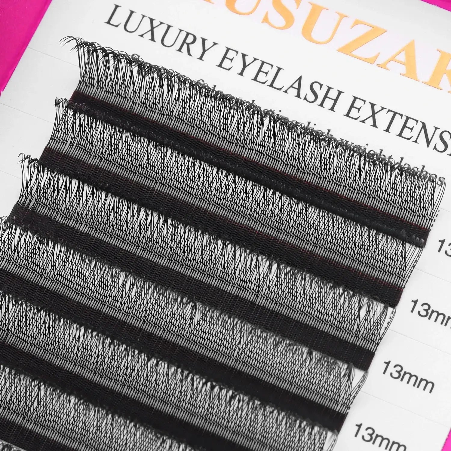 Rows of black, synthetic 13mm individual eyelash extensions arranged on an adhesive strip for professional application.