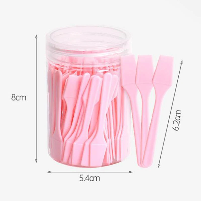 A container filled with many small, light pink plastic cosmetic spatulas for applying creams and masks.