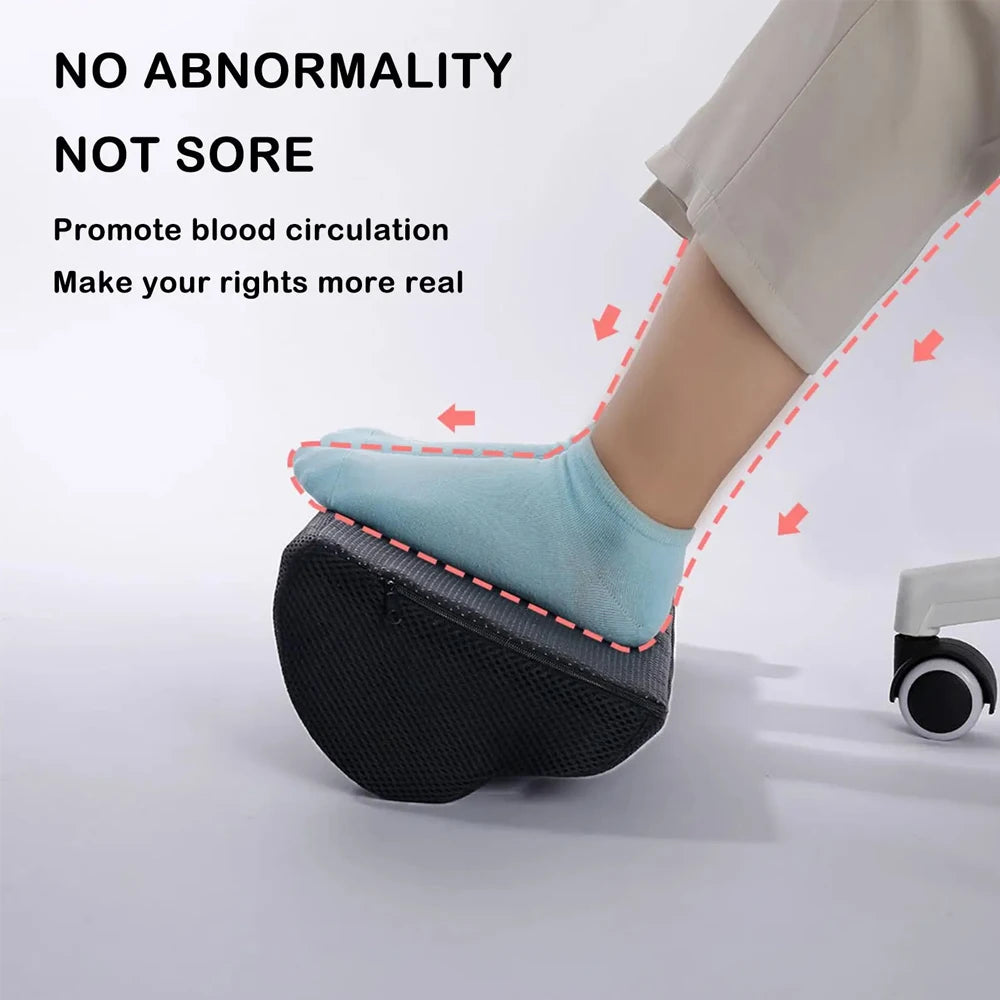 Ergonomic black memory foam foot rest under desk with mesh cover, supporting a foot to improve circulation at work.
