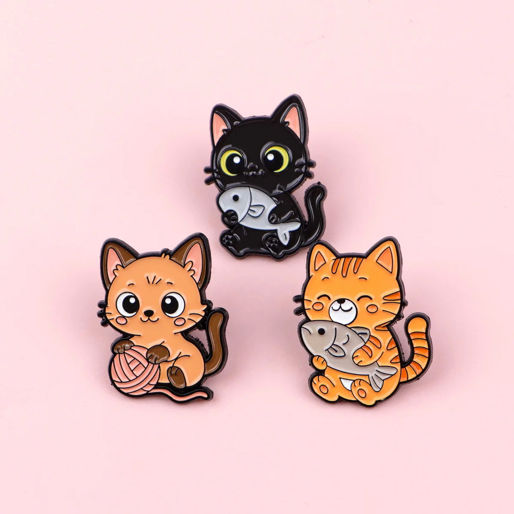 Cute cat enamel pins, featuring black and orange kittens with fish and yarn, perfect for backpacks and lapel jewelry.