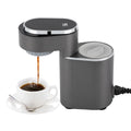 Modern dark gray compact coffee maker with digital temperature display brewing coffee into a white cup.