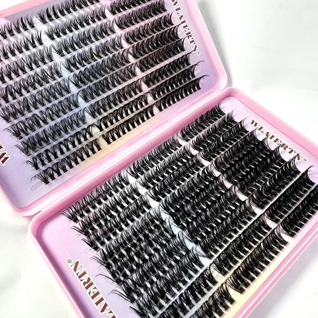 Black individual false eyelash clusters organized in rows within a two-compartment pink plastic storage case.