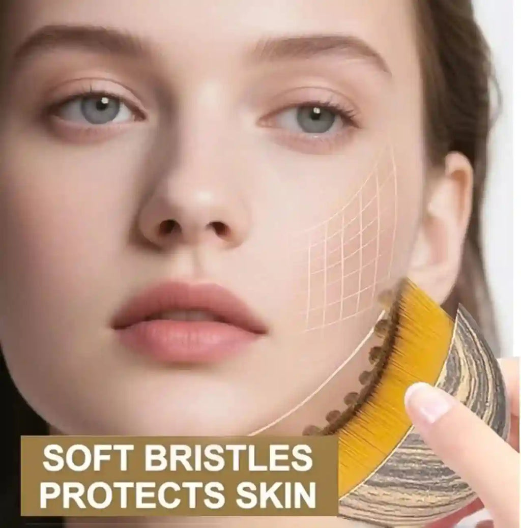 Hand holding an oval facial contouring brush with wood-grain finish and dense, soft golden bristles against a cheek.