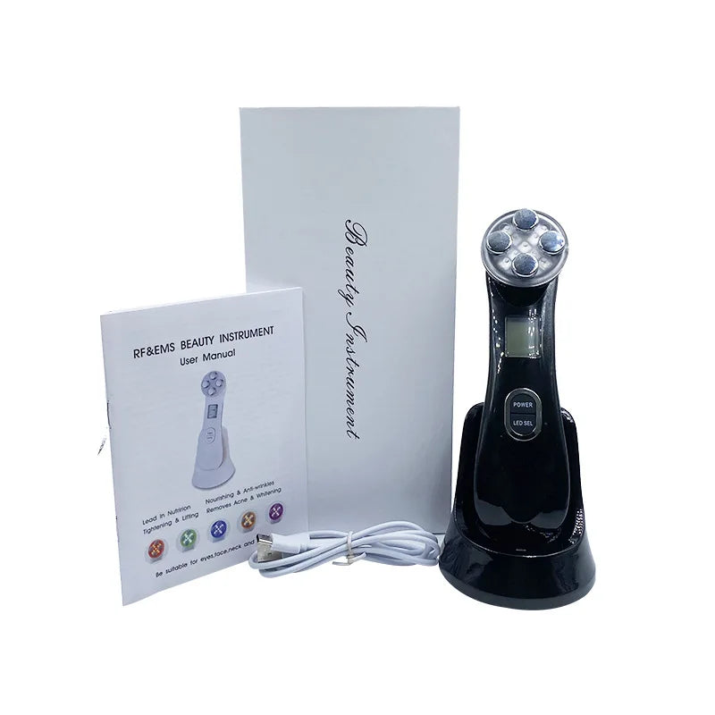 Black EMS facial massager on a charging base with a white box, user manual, and charging cable.