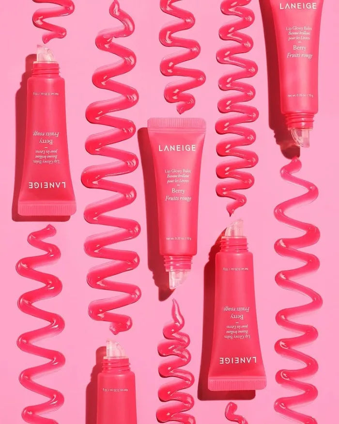 Laneige Berry Lip Glowy Balm tubes with glossy, hydrating pink lip balm swatches on a vibrant pink background.
