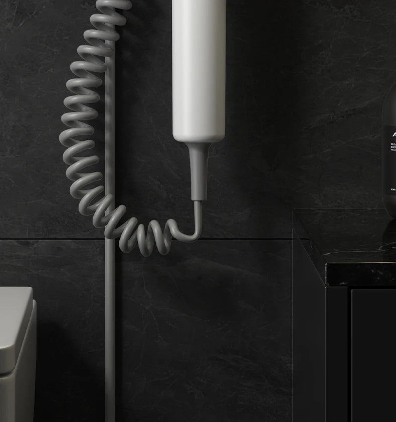 White wall-mounted hotel hair dryer with coiled cord for home or bathroom, featuring a modern, space-saving design.