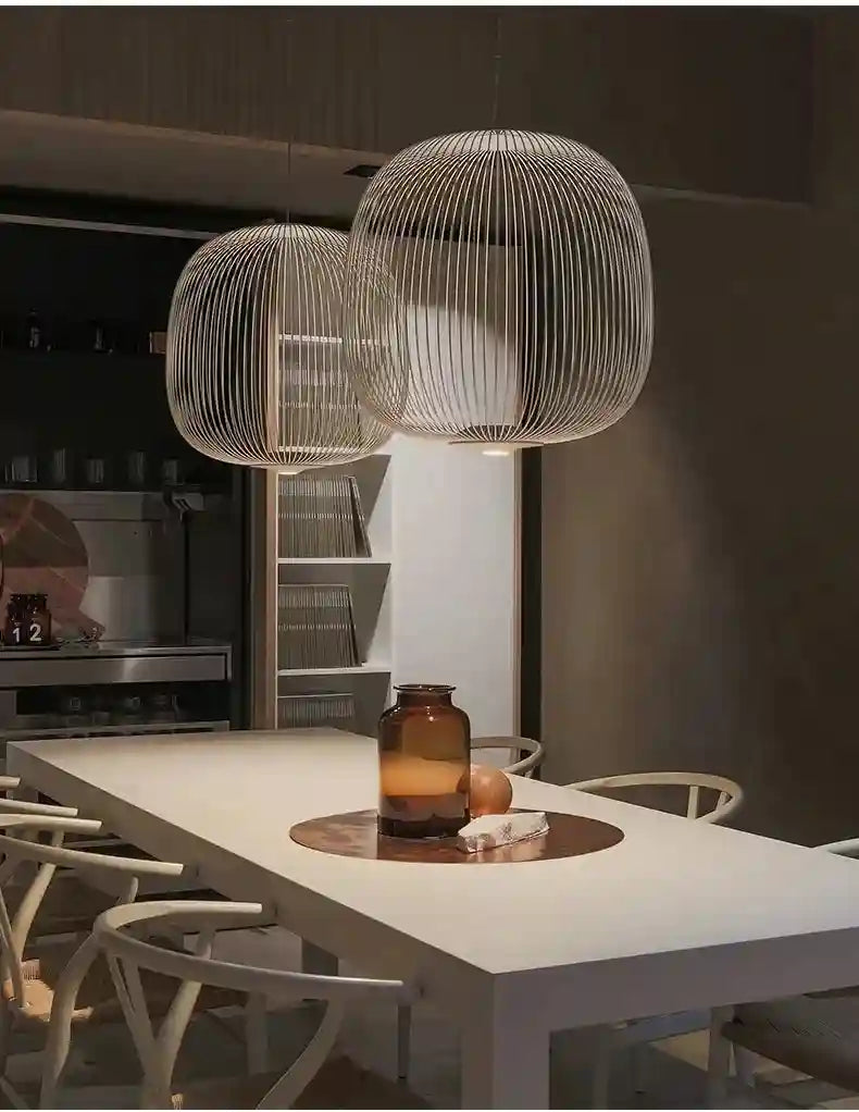 Two large, spherical white wire cage pendant lights suspended above a minimalist dining table.