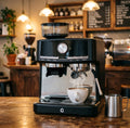 Gevi black espresso machine with integrated grinder, milk frother, and steam wand making coffee on a wooden table.
