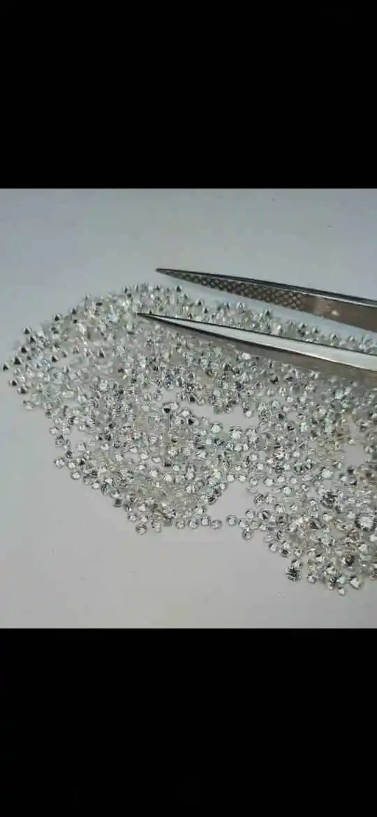 Loose round brilliant lab-grown diamond stones, metal tweezers resting among bright white gems