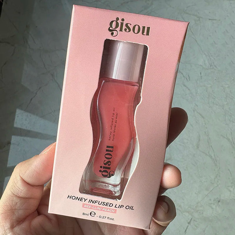 Gisou Honey Infused Lip Oil in Bee-Llini Peach, a moisturizing, glossy plumping lip care treatment in pink packaging.