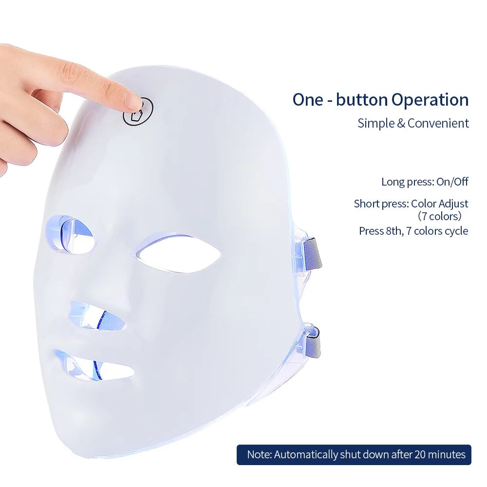 White plastic LED facial mask with a power button being pressed, showing blue light glow and straps on the side.