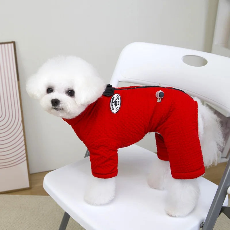 Small white dog wearing a warm, red waterproof winter jumpsuit for cozy outdoor protection and style.