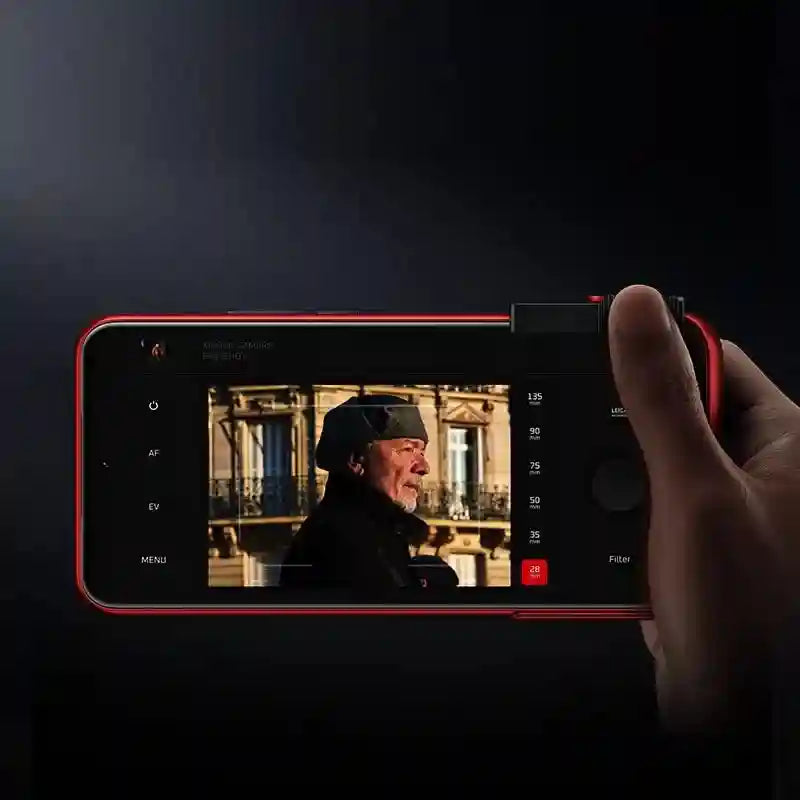 Red smartphone with a side-mounted camera shutter button and professional camera interface app, held horizontally.