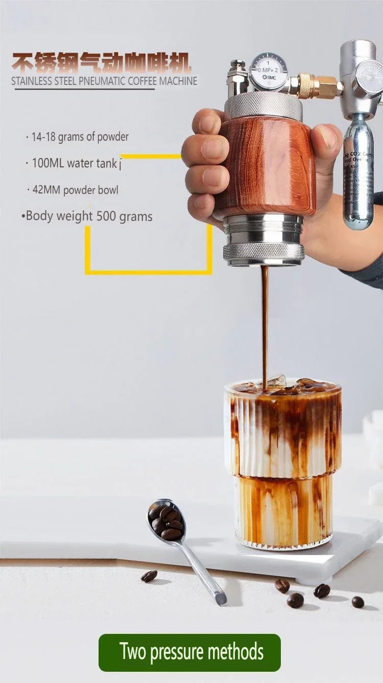 Stainless steel and wood pneumatic portable espresso maker with 100ml tank, pouring coffee into a glass.