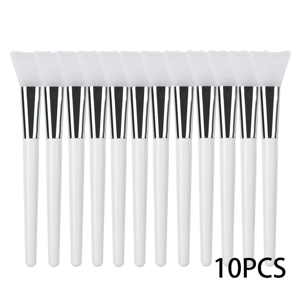 A row of 10 silicone face mask brushes with white handles, silver ferrules, and flat, flexible white silicone tips.