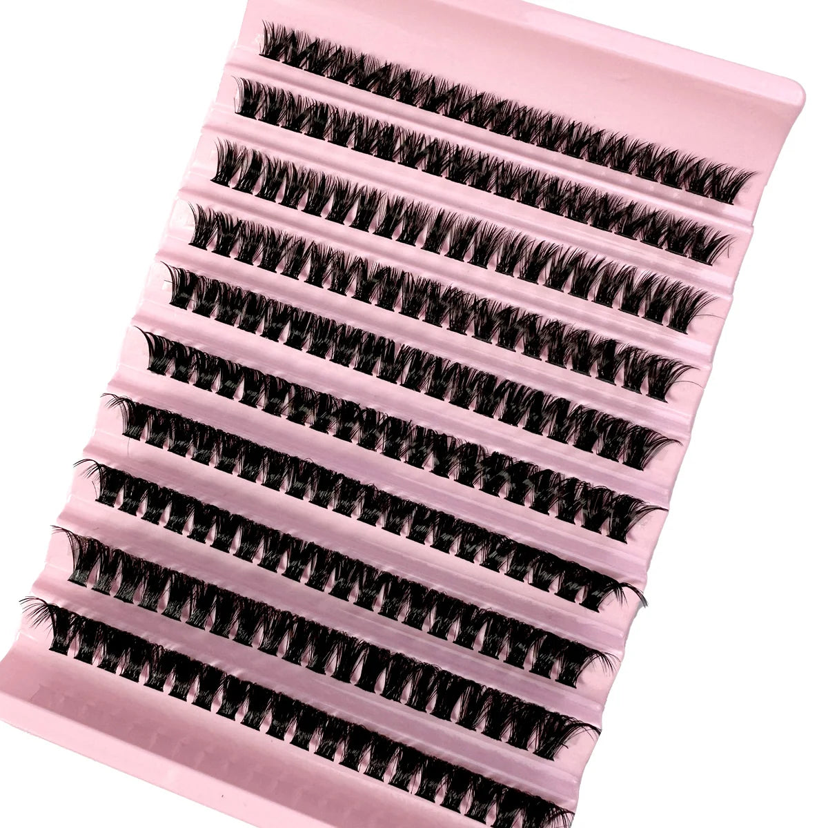 Black individual false eyelash clusters arranged in rows on a pale pink plastic tray for professional makeup