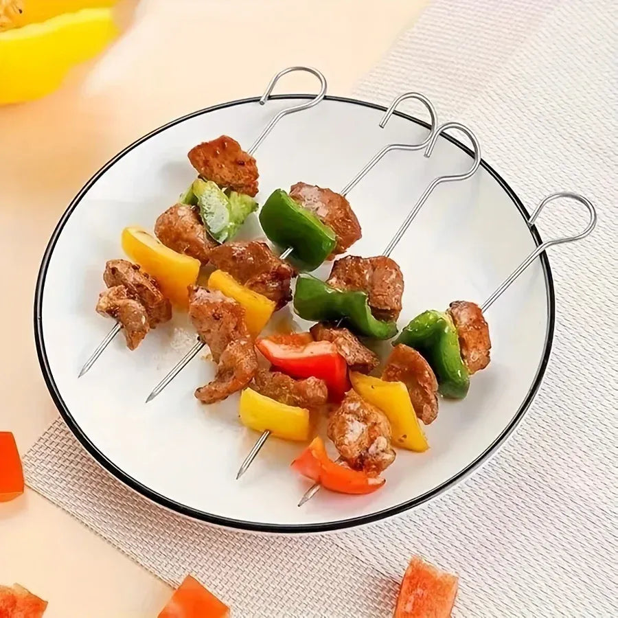 Four barbecue skewers with mixed meat and vegetables on a white plate