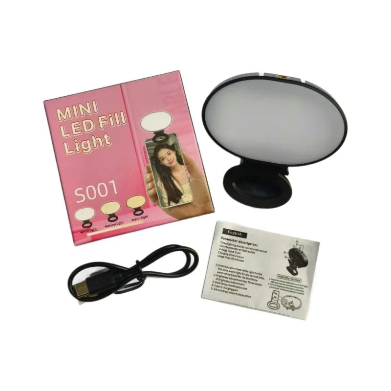 Mini LED fill light with clip, USB-C cable, and manual. Portable black oval light for smartphone photography.