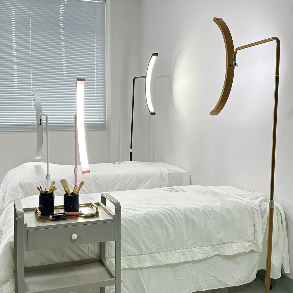 Curved LED floor lamps in gold, black, pink, and white for professional aesthetic and beauty treatment beds.