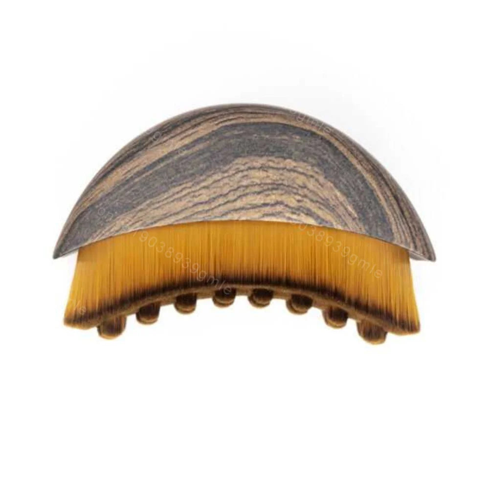 Curved facial sculpting brush with a brown wood-grain handle and dense, two-tone yellow and brown bristles.