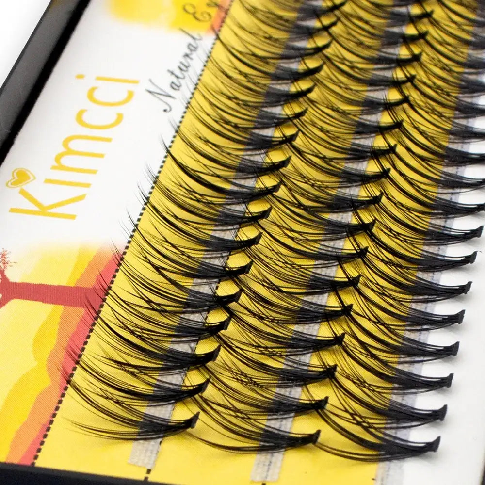 Tray of black individual 3D mink eyelash clusters, arranged in rows on a yellow Kimcci-branded packaging card.