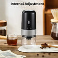 Portable black electric coffee grinder with metallic textured grip, transparent bean container, and USB charging port.