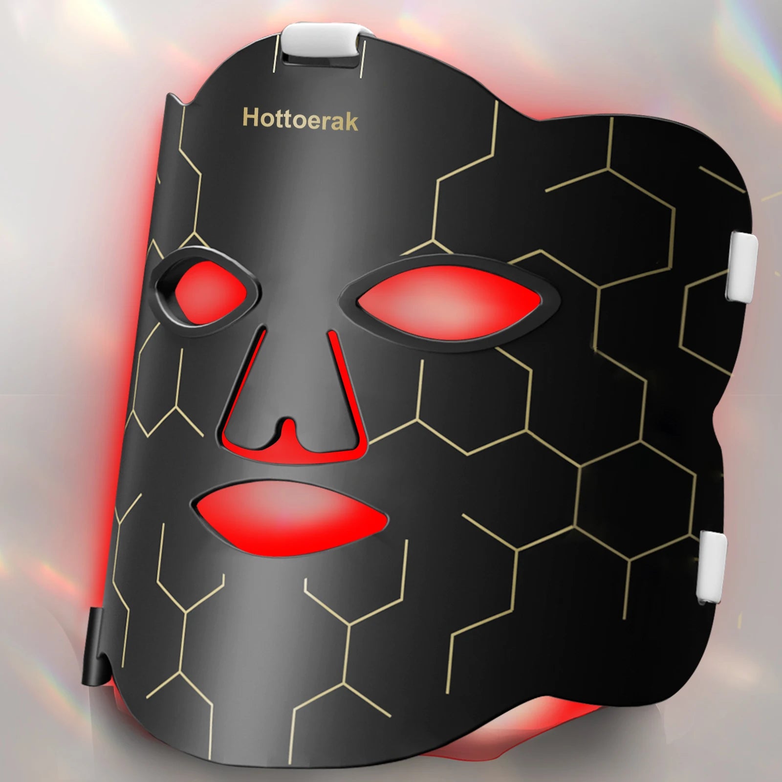 Hottoerak flexible black silicone LED face mask with gold hexagon pattern emitting therapeutic red light for skincare.