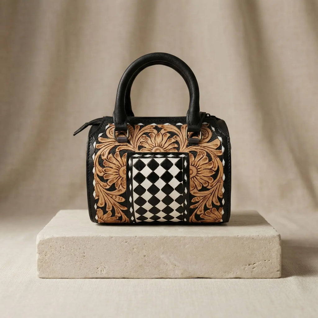 Luxury leather weekender trunk with hand-tooled floral carvings and a black and white checkered center panel.