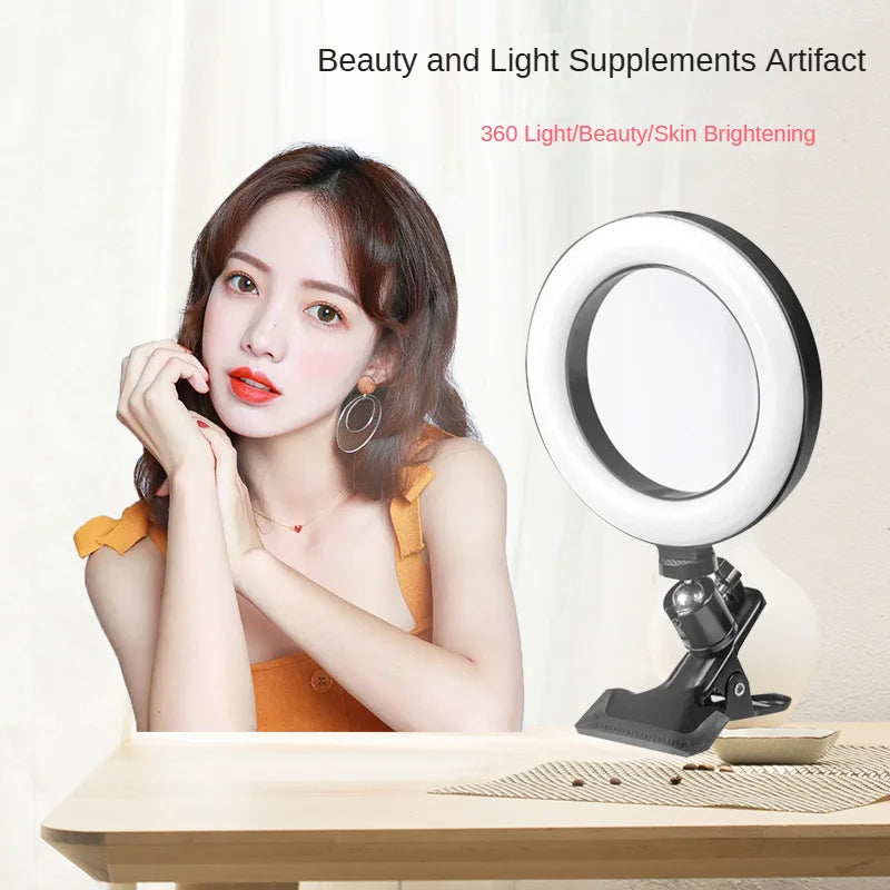 Small black ring light with a clip-on base, used for selfie or makeup lighting, shown next to a woman.
