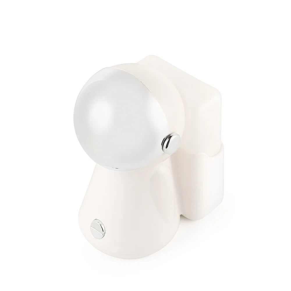 White astronaut-shaped table lamp with a spherical head, rounded body, and silver accents for ambient room lighting.