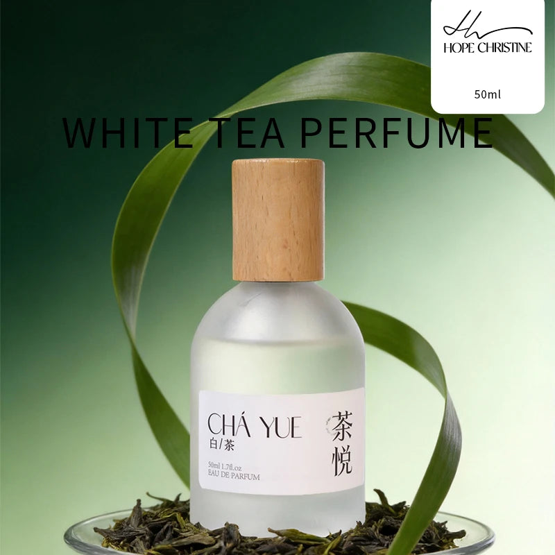 Hope Christine unisex white tea perfume in a frosted glass bottle with a wooden cap, set on green tea leaves.
