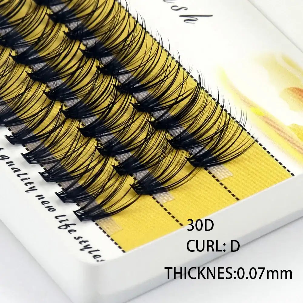 A box of black 30D individual eyelash cluster extensions with a D-curl and 0.07mm thickness on a yellow tray.