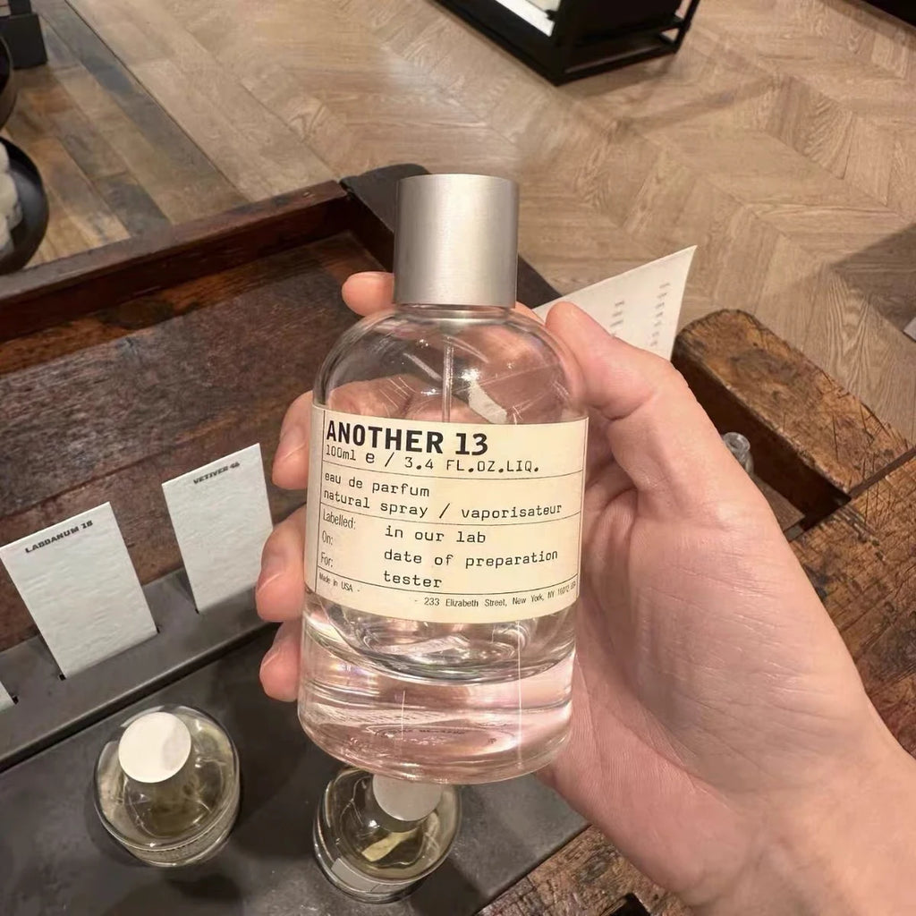 Another 13 eau de parfum in a 100ml clear glass spray bottle with a silver cap, held in hand.