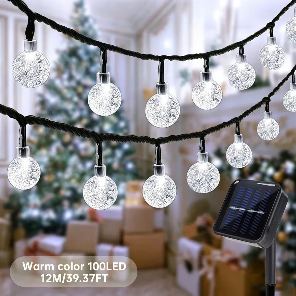 Warm LED globe string lights with sparkling round bulbs and a solar panel stake, indoor patio scene.