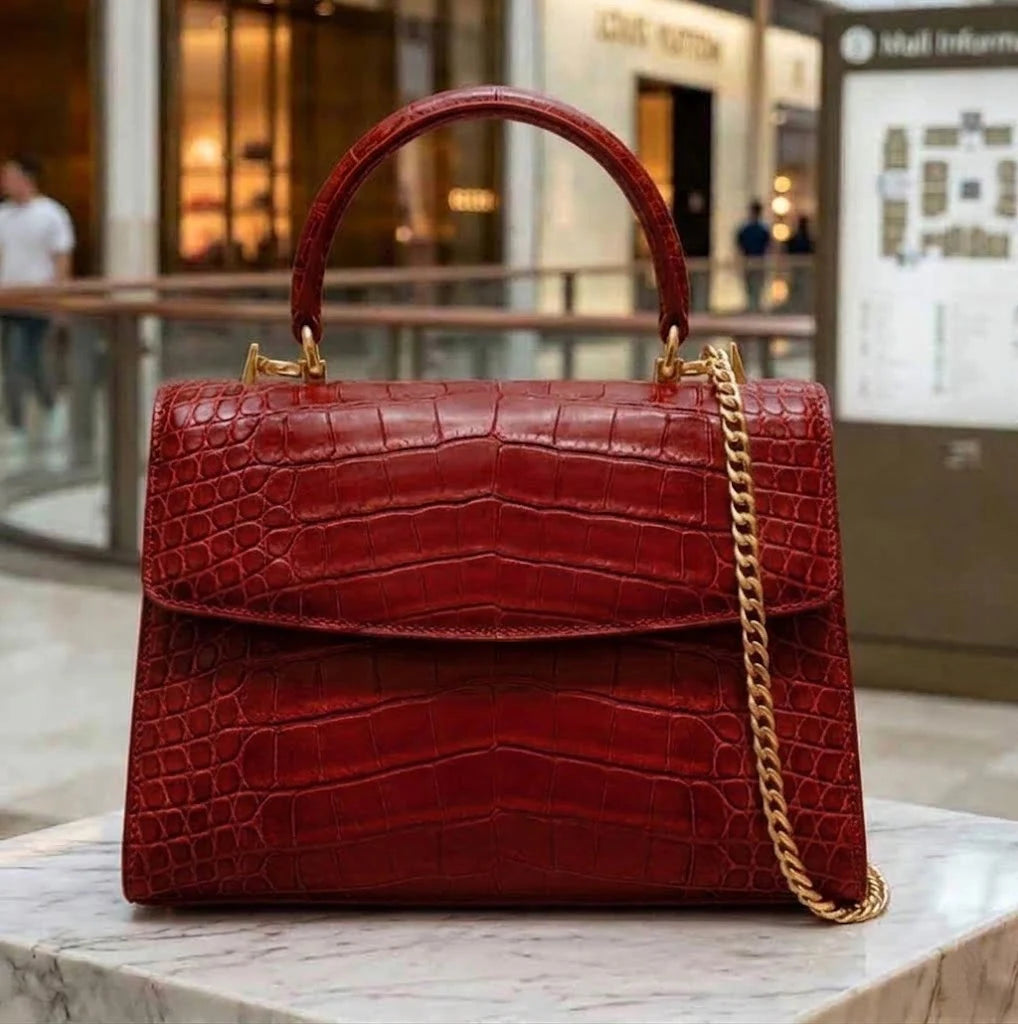 Red vintage-style genuine alligator leather designer handbag with a gold chain strap and top handle.