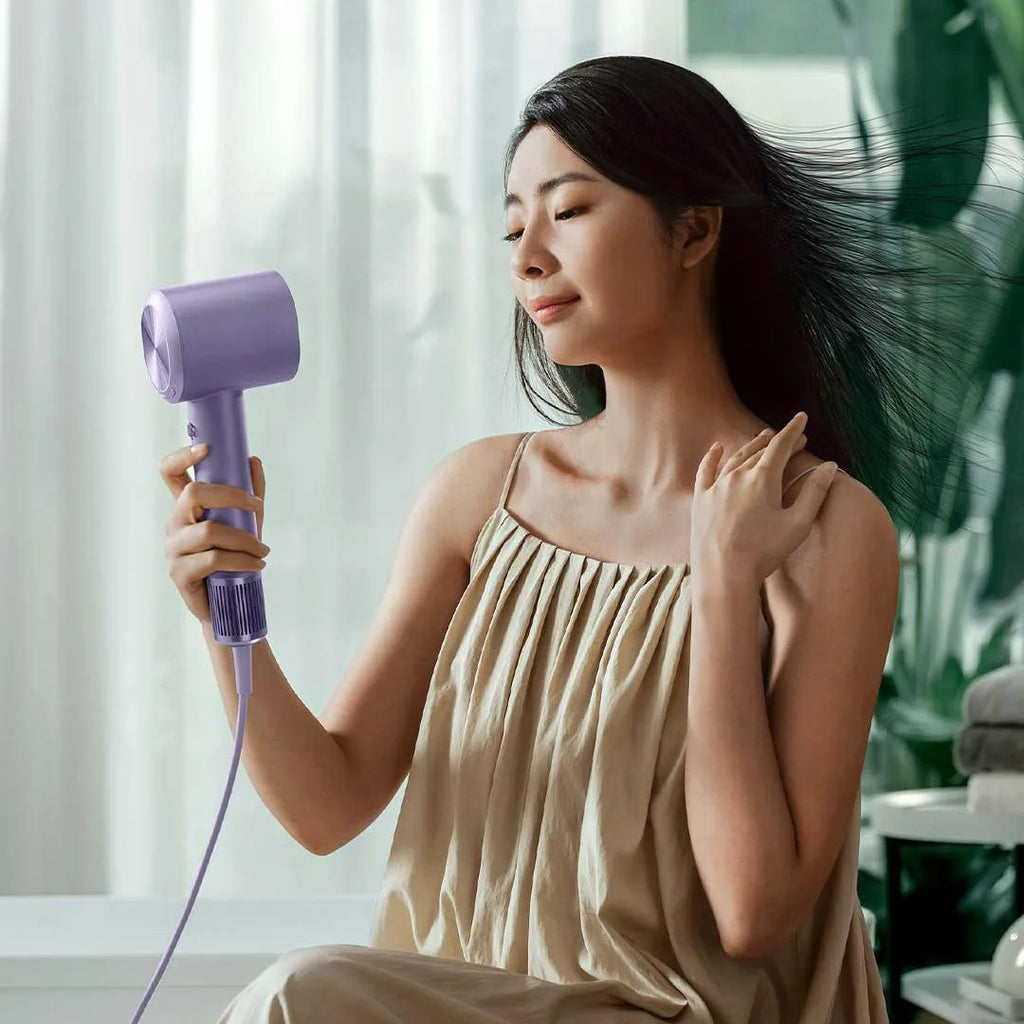 Woman using purple MIJIA H701 high-speed hair dryer for quick, professional ionic hair care and sleek styling.