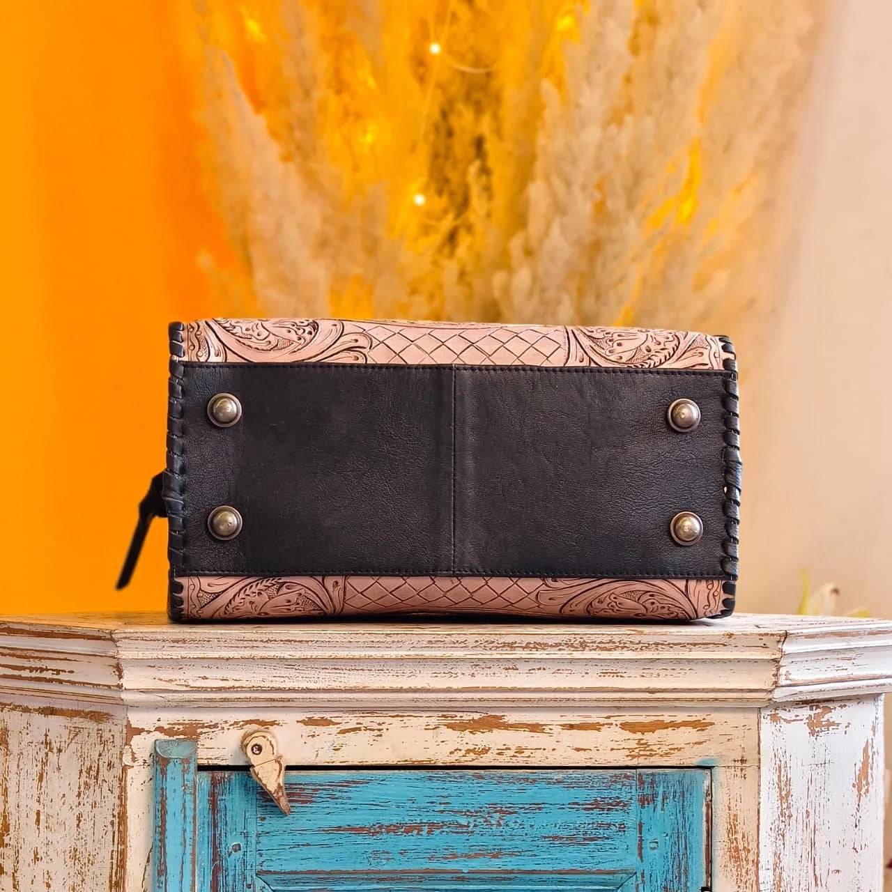 Hand-tooled floral genuine leather weekender trunk, black and beige, with metal feet and braided side stitching.