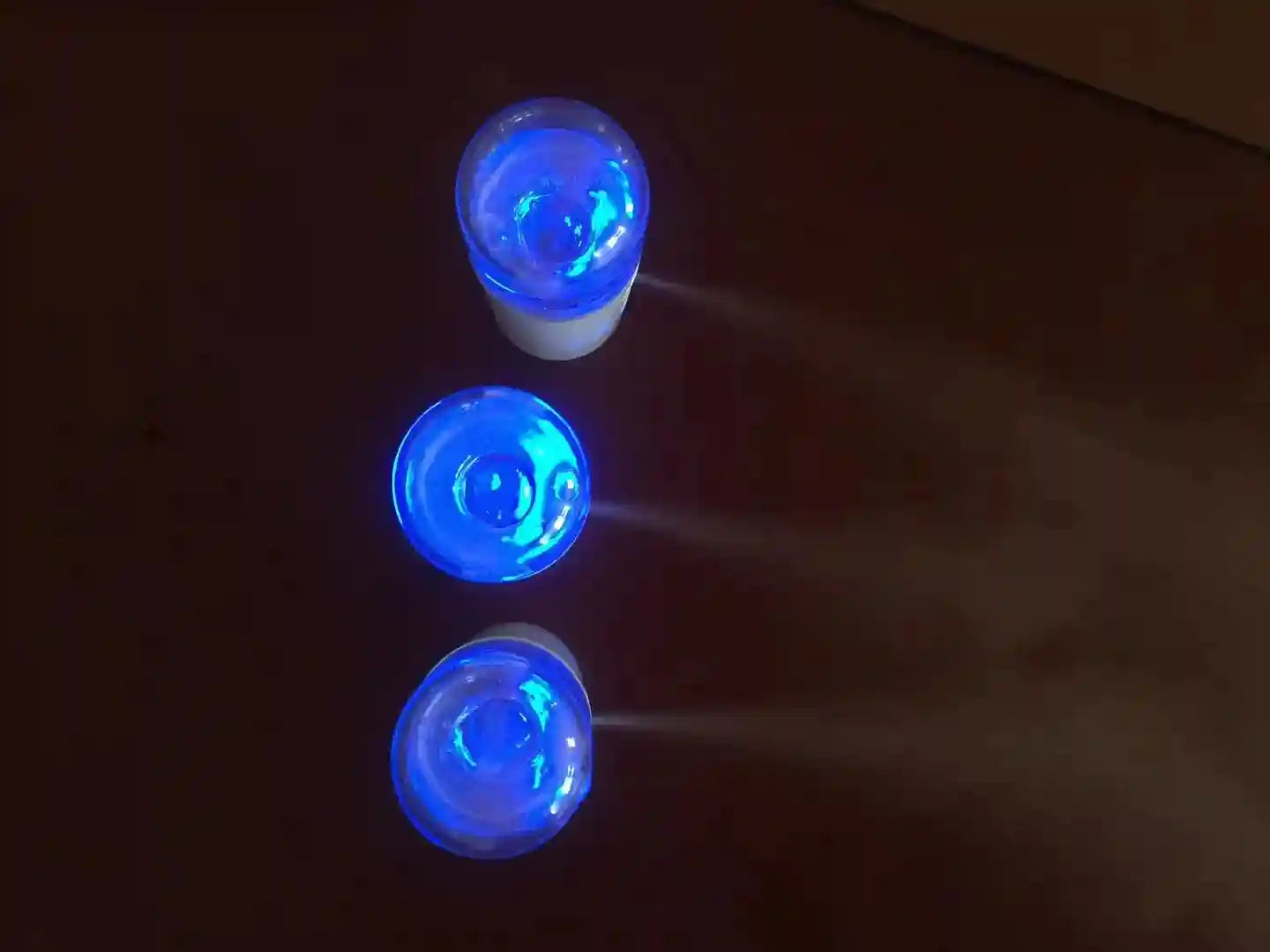 Portable nano facial mister with blue LED light emitting a fine hydrating mist for skin care and eyelash extensions.