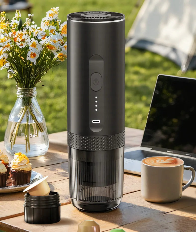 Black portable electric espresso maker with USB-C charging for outdoor coffee brewing, standing on a garden table.