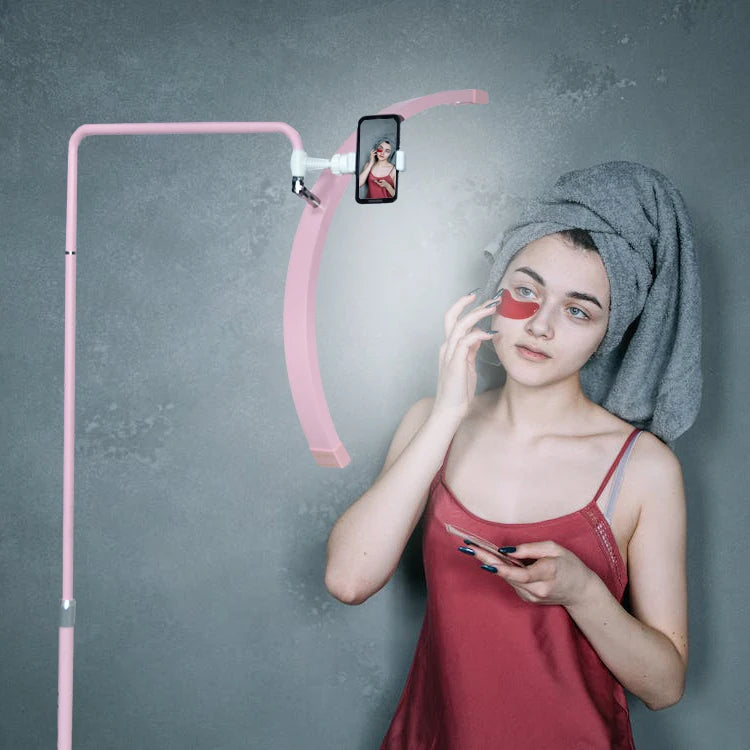 Pink over-the-head smartphone stand with a curved arc, used for hands-free video recording or selfies.