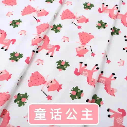 Tidesmit white knit jersey fabric featuring a repeating pink princess, unicorn, and green frog pattern for baby clothing.