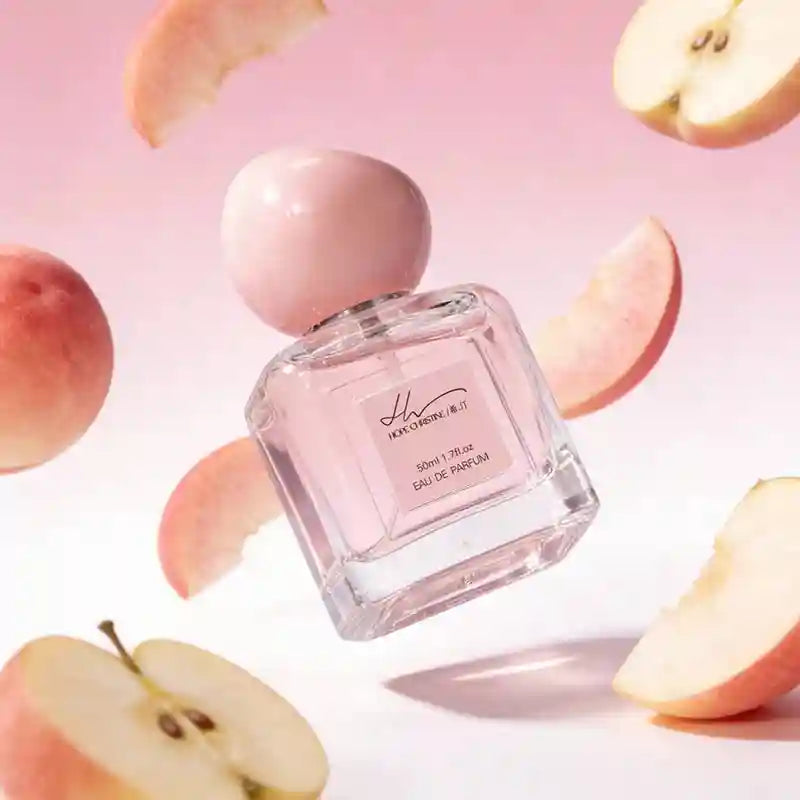 Hope Christine Peach EDP for Women: 50ml square glass bottle with round pink cap, surrounded by fresh peach slices.