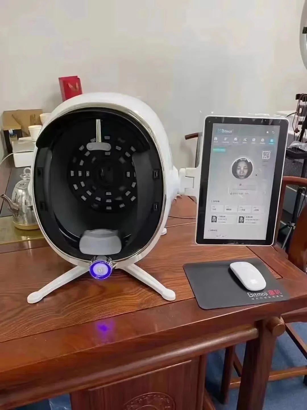 White facial skin analysis machine with internal sensor lights and an attached tablet screen for skin data display.