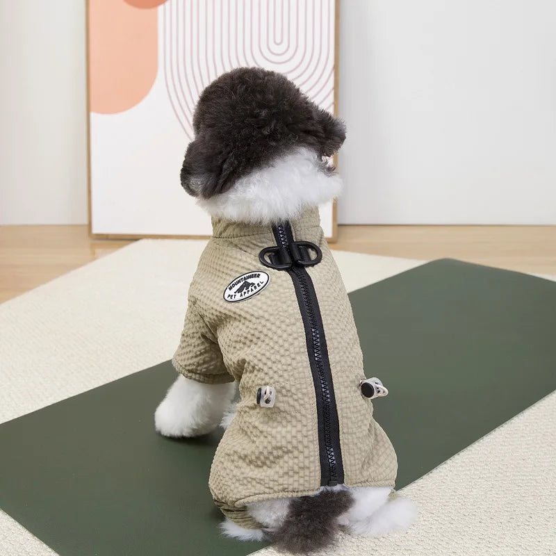 Small dog wearing a beige, waterproof four-leg winter jumpsuit with a zipper to keep puppies warm and dry.