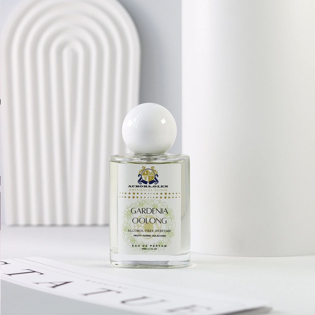 Glass perfume bottle with white spherical cap, Gardenia Oolong label, clear liquid fragrance on white minimalist surface.