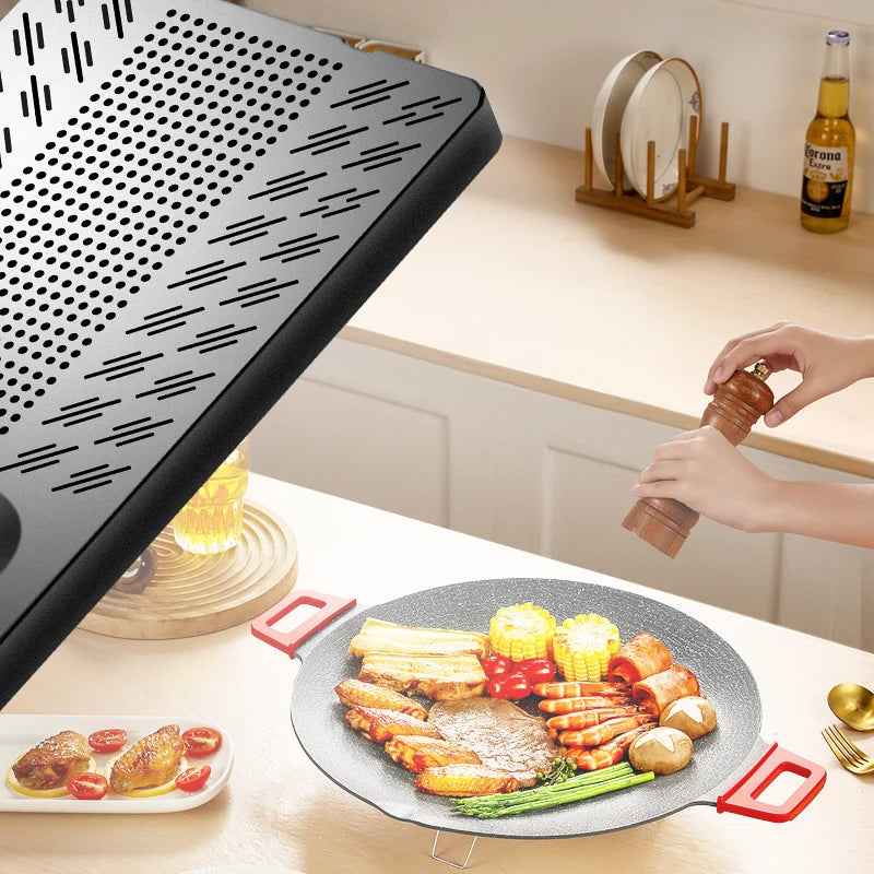 Round granite-textured grill pan with red handles, filled with grilled meat, seafood, and vegetables on a table.