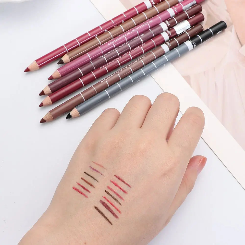 Professional waterproof lip liner and eyeliner pencils in various shades with pigment swatches on a hand.